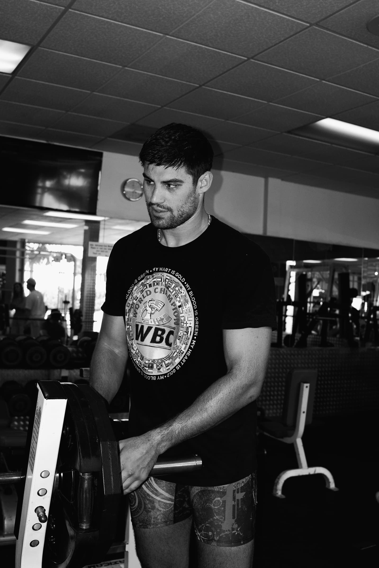 Black and white portrait at the weight rack in a WBC champion shirt
