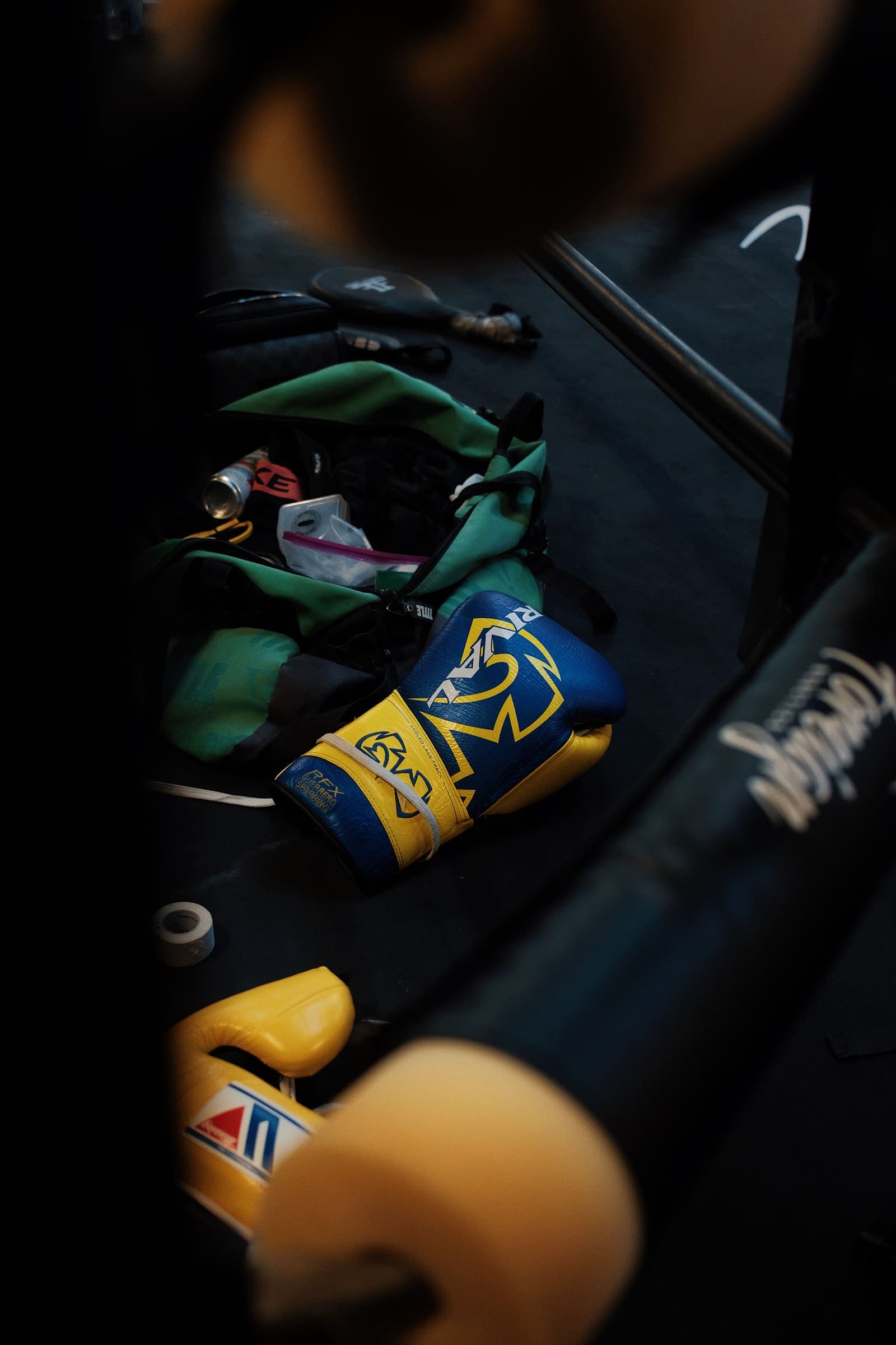 Blue and yellow lace-up sparring gloves resting on the ring floor