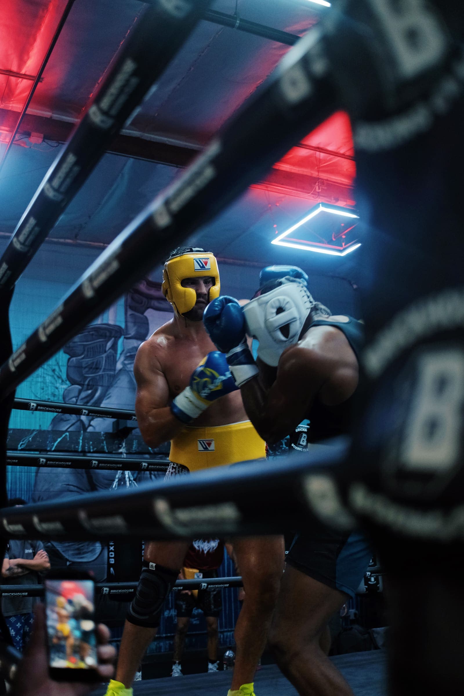 Sparring round seen through the ring ropes, red light overhead